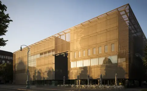 Moderne Architektur der Kunsthalle Mannheim im goldenen Abendlicht. Vor dem Gebäude laden Tische und Stühle zum Verweilen ein.