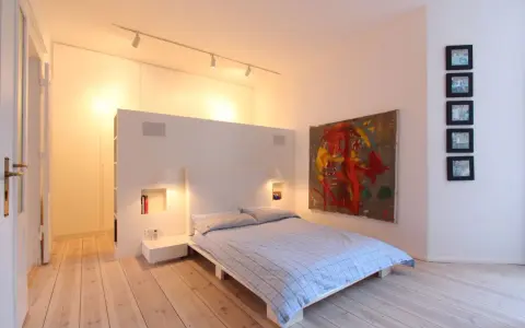 Modernes Schlafzimmer mit Bett, Kunstwerk und Einbauschränken. Tolle Renovierungsideen für minimalistische Räume.
