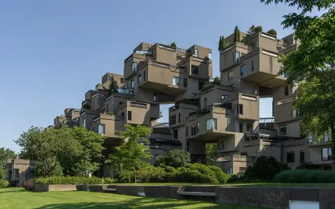 Ein beeindruckendes Beispiel brutalistischer Architektur: Betonblöcke stapeln sich zu einer futuristischen Wohnanlage, umgeben von Grün.