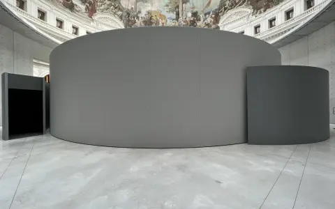 Graue, runde Installationen im Inneren eines Gebäudes mit einer Deckenmalerei, die an eine historische **Bourse de commerce** erinnert.