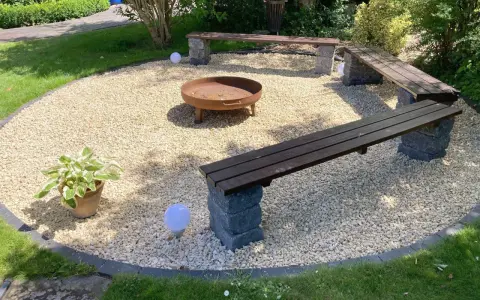 Gemütliche Kies Garten Sitzecke mit Feuerstelle und Bänken. Perfekt für laue Sommerabende.