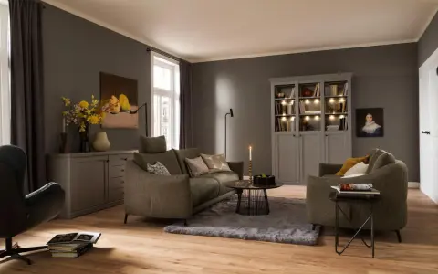 Gemütliches Wohnzimmer mit einem weichen, grauen Teppich unter dem Sofa und einem Sessel.