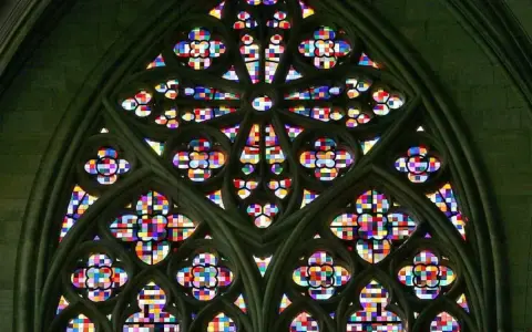Ein farbenprächtiges Rosettenfenster im gotischen Baustil, das durch seine filigrane Steinarchitektur und das leuchtende Glas beeindruckt.