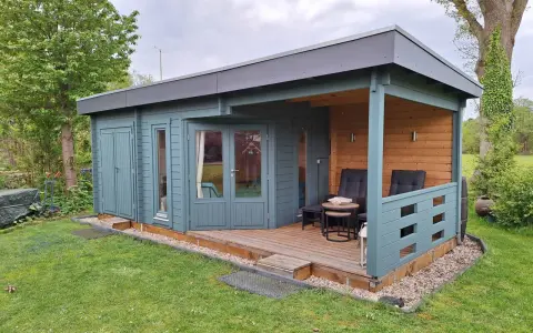 Ein blaugrünes Gartenhaus mit Veranda und Sitzgelegenheiten. Tolle Gartenhaus Farben Ideen für Ihr grünes Paradies.