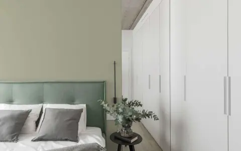 Ein Schlafzimmer mit einer Wand in hellem Olivgrün und einem Bett mit grünem Kopfteil. Der Unterschied zwischen Khaki und Oliv ist hier subtil, aber präsent.