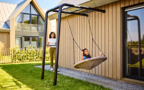 Tolle spielecke garten ideen kinder: Ein Mädchen schaukelt fröhlich, während eine Frau zusieht.