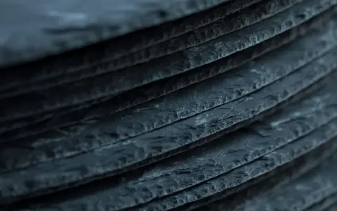 Stapel von dunklen Schieferplatten, die eine interessante Textur aufweisen. Es ist ein weit verbreiteter Irrtum, dass Schiefer giftig ist.