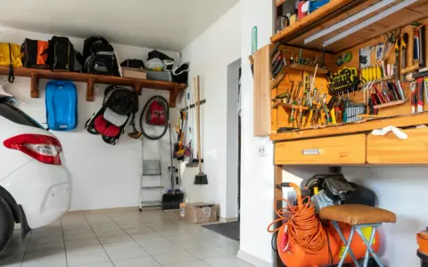 Praktische garage einrichten ideen: Werkzeugwand, Regale mit Taschen und ein Kompressor schaffen Ordnung.