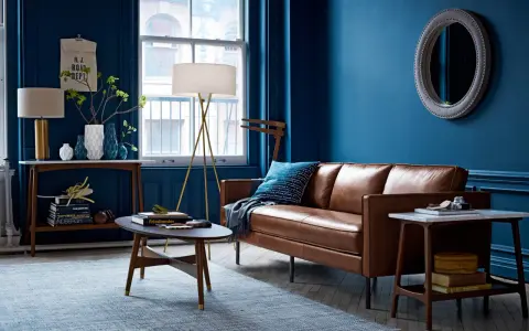Ein Wohnzimmer mit braunem Ledersofa und blauen Wänden. Das Braun ist die perfekte gegenfarbe von braun, die dem Raum Tiefe verleiht.