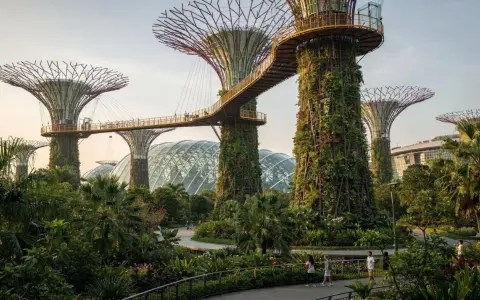Futuristische Supertrees und Gewächshäuser in den Gardens by the Bay, Singapur, mit Menschen, die auf Wegen spazieren.