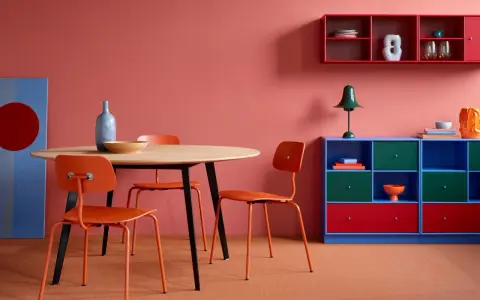 Ein Esszimmer mit roten Akzenten: Orange Stühle, ein blauer Schrank und rote Regale zeigen, welche Farben passen zu Rot.