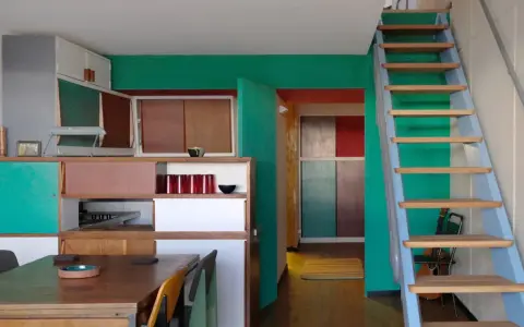 Einblick in eine Wohnung im Stil von Le Corbusier in Berlin: bunte Wände, Holzmöbel und eine Leiter.