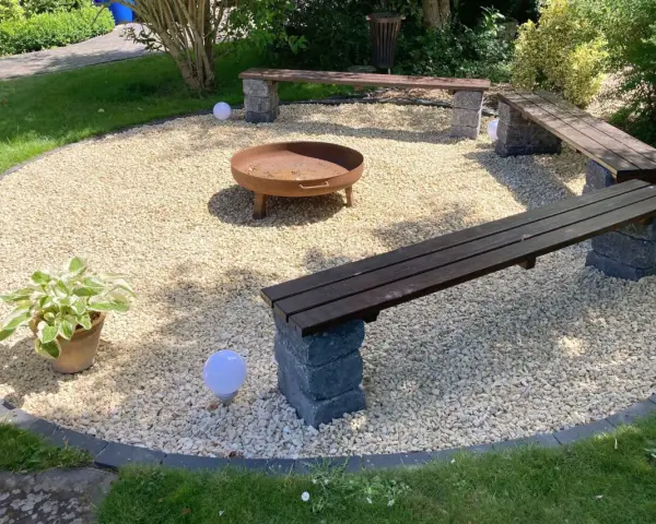 Gemütliche Kies Garten Sitzecke mit Feuerstelle und Bänken. Perfekt für laue Sommerabende.