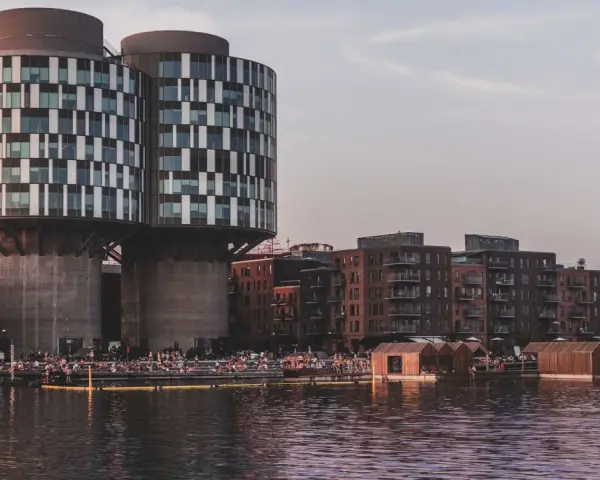 Moderne Architektur und schwimmende Holzhäuser am Wasser in Nordhavn Kopenhagen. Menschen genießen die Abendsonne.