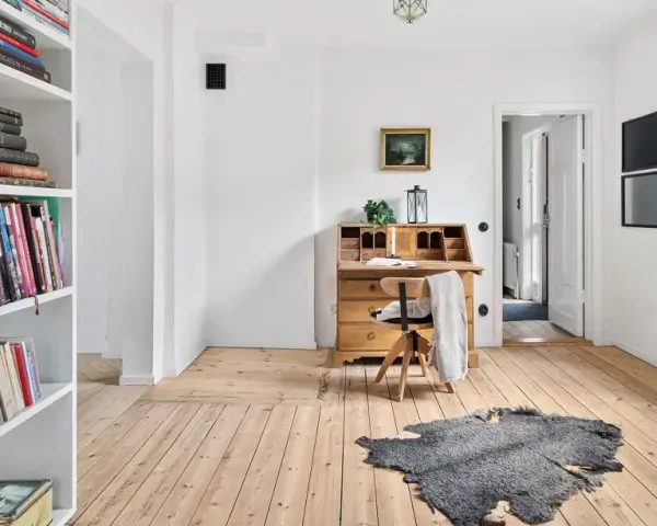 Ein heller Raum mit Bücherregalen, einem antiken Schreibtisch und Pflanzen. Perfekt für ausmisten tipps, um Ordnung zu schaffen.