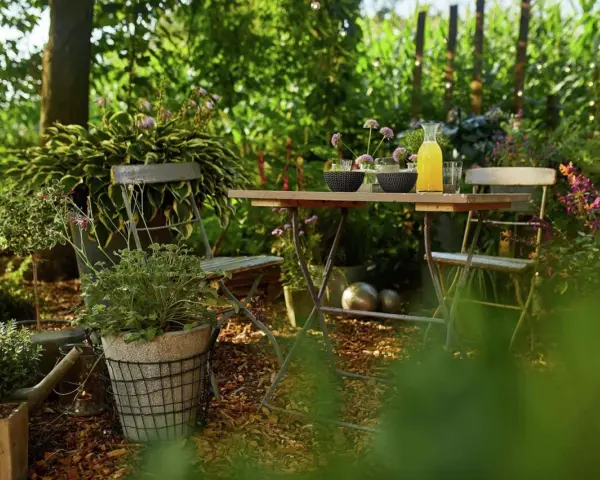 Gemütliche Gartenecke mit Tisch und Stühlen, umgeben von üppigem Grün. Rindenmulch garten ideen für eine natürliche Atmosphäre.