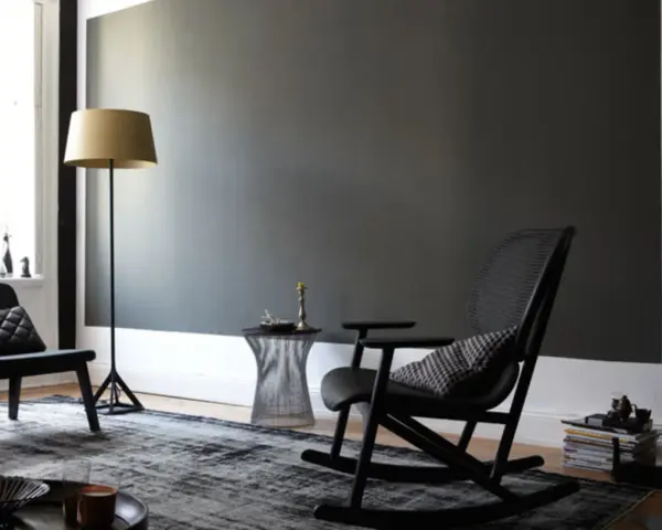 Stilvolles Wohnzimmer mit dunkler wand schwarz streichen Idee. Schwarzer Schaukelstuhl, Sessel, Stehlampe und Teppich.