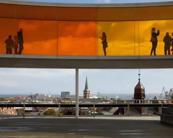 Silhouetten von Menschen auf dem Regenbogenpanorama des Kunstmuseums Aarhus. Blick auf die Stadt und das Meer.