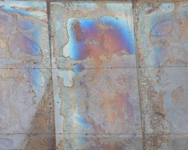 Verwittertes Metall mit schillernden Farben, die die Bedeutung von Patina zeigen. Rostige und blaue Muster erzählen eine Geschichte der Zeit.