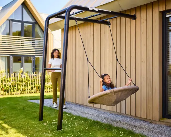 Tolle spielecke garten ideen kinder: Ein Mädchen schaukelt fröhlich, während eine Frau zusieht.