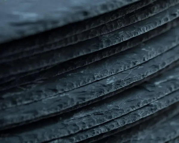 Stapel von dunklen Schieferplatten, die eine interessante Textur aufweisen. Es ist ein weit verbreiteter Irrtum, dass Schiefer giftig ist.