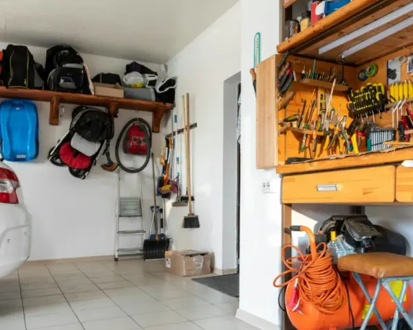 Praktische garage einrichten ideen: Werkzeugwand, Regale mit Taschen und ein Kompressor schaffen Ordnung.