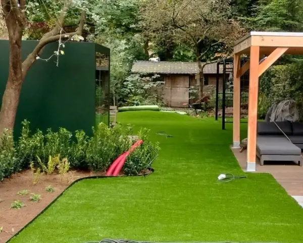 Moderne Gartenaufteilung mit Kunstrasen, Holzpavillon, Lounge-Möbeln und grüner Wand. Tolle Ideen für Ihren Garten!