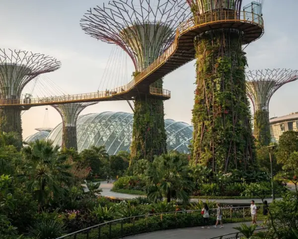 Futuristische Supertrees und Gewächshäuser in den Gardens by the Bay, Singapur, mit Menschen, die auf Wegen spazieren.