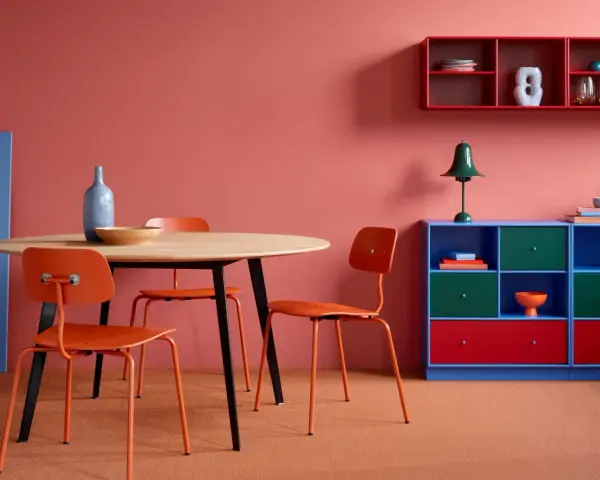 Ein Esszimmer mit roten Akzenten: Orange Stühle, ein blauer Schrank und rote Regale zeigen, welche Farben passen zu Rot.