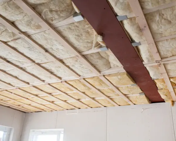 Decke mit Holzbalken und Dämmung. Hier sieht man, was ist Glaswolle: ein isolierendes Material, das in Hohlräume eingebracht wird.