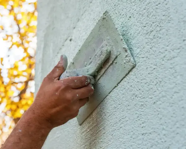 Hand bearbeitet eine Fassade mit einer Kelle. Verschiedene Putztechniken fassade werden hier angewendet, um eine rustikale Textur zu erzeugen.