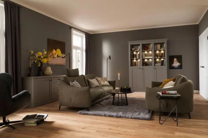 Gemütliches Wohnzimmer mit einem weichen, grauen Teppich unter dem Sofa und einem Sessel.