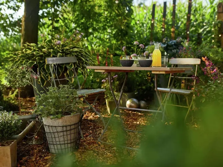 Gemütliche Gartenecke mit Tisch und Stühlen, umgeben von üppigem Grün. Rindenmulch garten ideen für eine natürliche Atmosphäre.