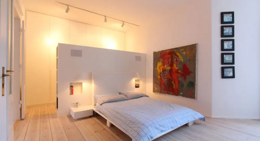 Modernes Schlafzimmer mit Bett, Kunstwerk und Einbauschränken. Tolle Renovierungsideen für minimalistische Räume.