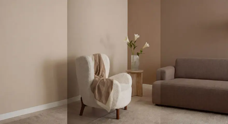 Gemütliches Wohnzimmer mit einem weißen Teddy-Sessel, einer braunen Couch und einer Vase mit Lilien. Warme Farben dominieren die Szene.
