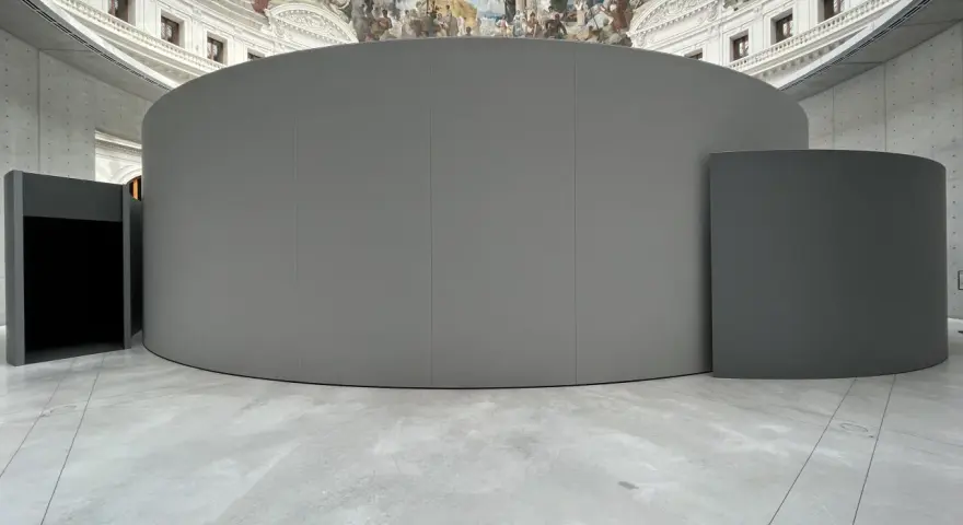 Graue, runde Installationen im Inneren eines Gebäudes mit einer Deckenmalerei, die an eine historische **Bourse de commerce** erinnert.
