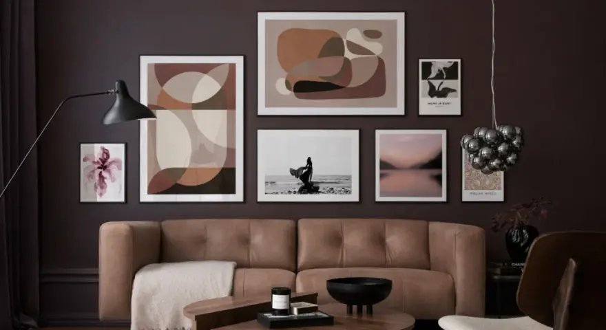 Braune und beige Töne passen wunderbar zu Schwarz. Ein stilvolles Wohnzimmer mit brauner Ledercouch, Kunstwerken und einem Couchtisch.