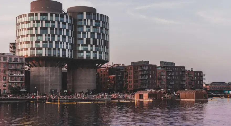 Moderne Architektur und schwimmende Holzhäuser am Wasser in Nordhavn Kopenhagen. Menschen genießen die Abendsonne.