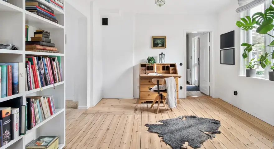 Ein heller Raum mit Bücherregalen, einem antiken Schreibtisch und Pflanzen. Perfekt für ausmisten tipps, um Ordnung zu schaffen.