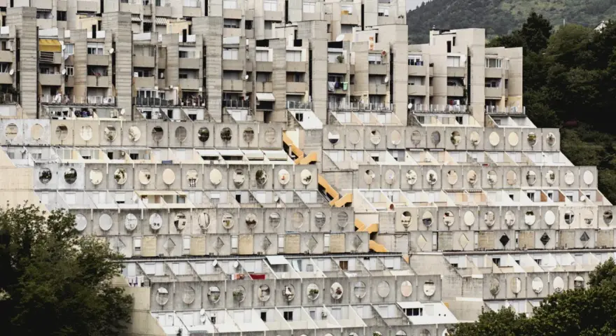 Massive Wohnanlage im Stil der brutalismus architektur, mit terrassierten Ebenen und vielen runden Fenstern.