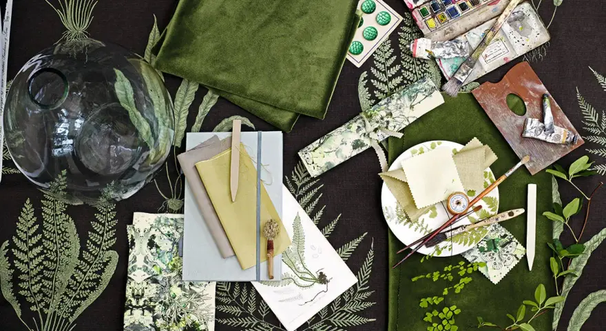 Ein Moodboard mit grünen Stoffen, Aquarellfarben, Pinseln und Farnmotiven. Hier wird gezeigt, was ein Moodboard ist: eine Sammlung von Inspirationen.