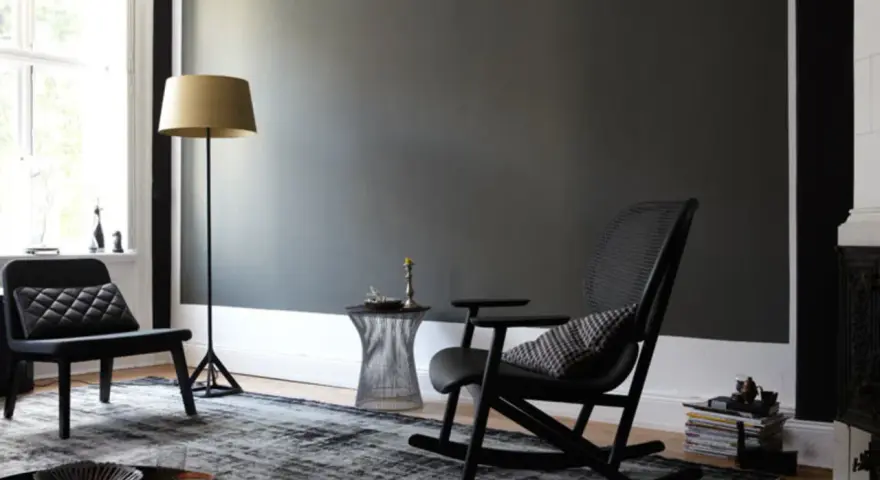 Stilvolles Wohnzimmer mit dunkler wand schwarz streichen Idee. Schwarzer Schaukelstuhl, Sessel, Stehlampe und Teppich.