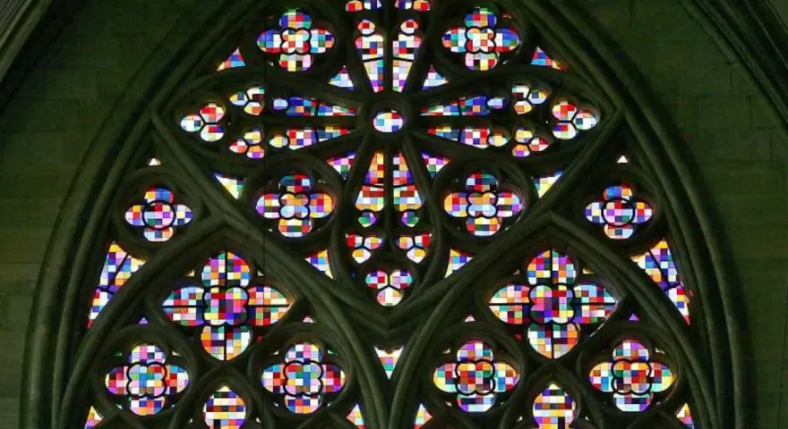 Ein farbenprächtiges Rosettenfenster im gotischen Baustil, das durch seine filigrane Steinarchitektur und das leuchtende Glas beeindruckt.