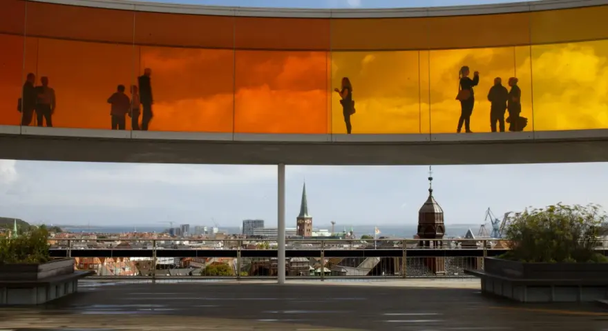 Silhouetten von Menschen auf dem Regenbogenpanorama des Kunstmuseums Aarhus. Blick auf die Stadt und das Meer.