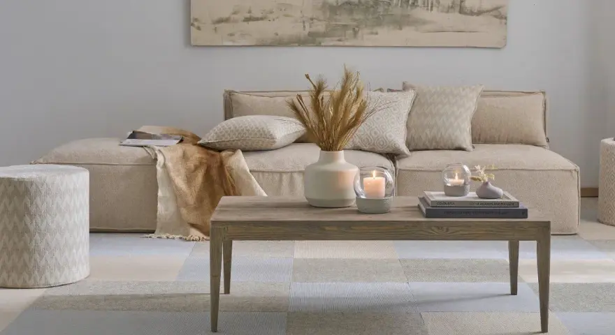 Gemütliches, **ästhetisches Zimmer** mit beigem Sofa, Holztisch, Kerzen und Deko.