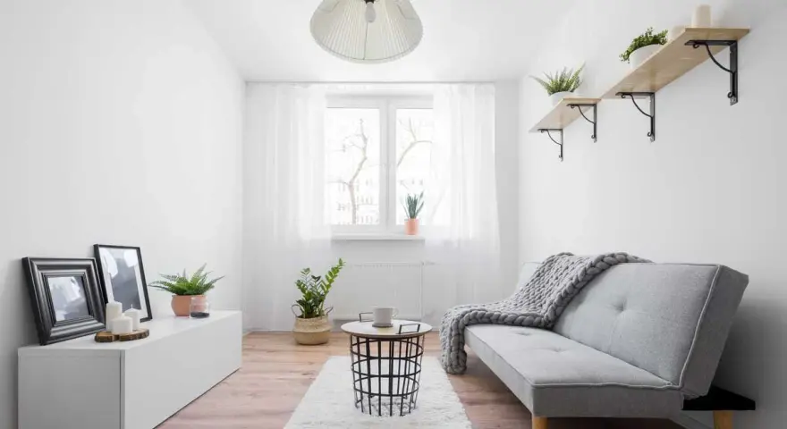 Ein gemütliches Schlauchzimmer einrichten: Helles Sofa, Teppich, Beistelltisch, Pflanzen und Bilder schaffen eine wohnliche Atmosphäre.