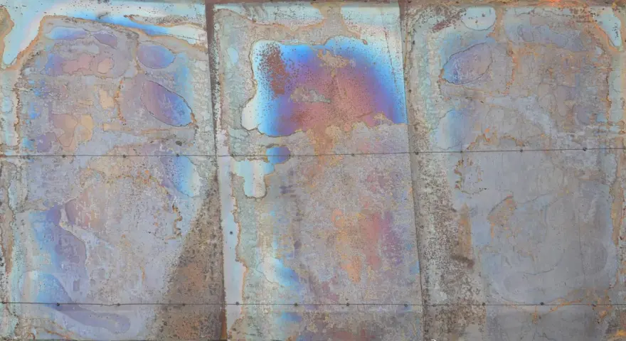 Verwittertes Metall mit schillernden Farben, die die Bedeutung von Patina zeigen. Rostige und blaue Muster erzählen eine Geschichte der Zeit.