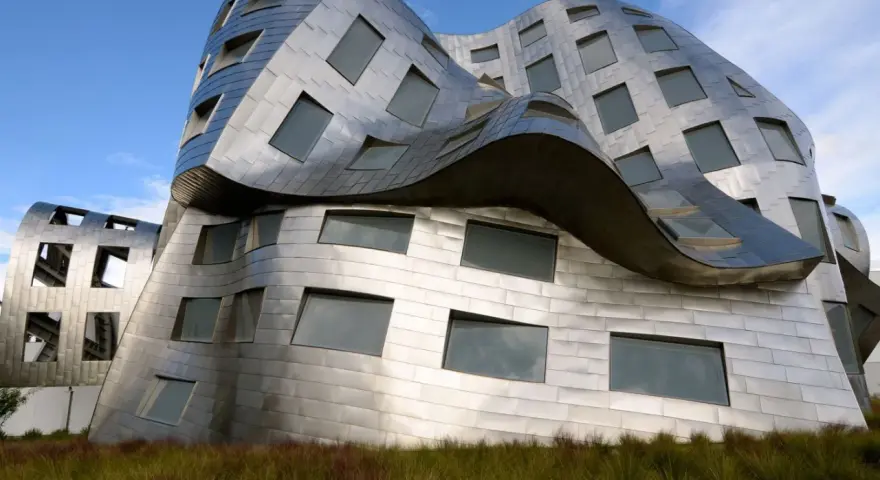 Ein futuristisches Gebäude mit geschwungenen Metallfassaden, typisch für Frank Gehry Bauwerke, ragt aus hohem Gras empor.