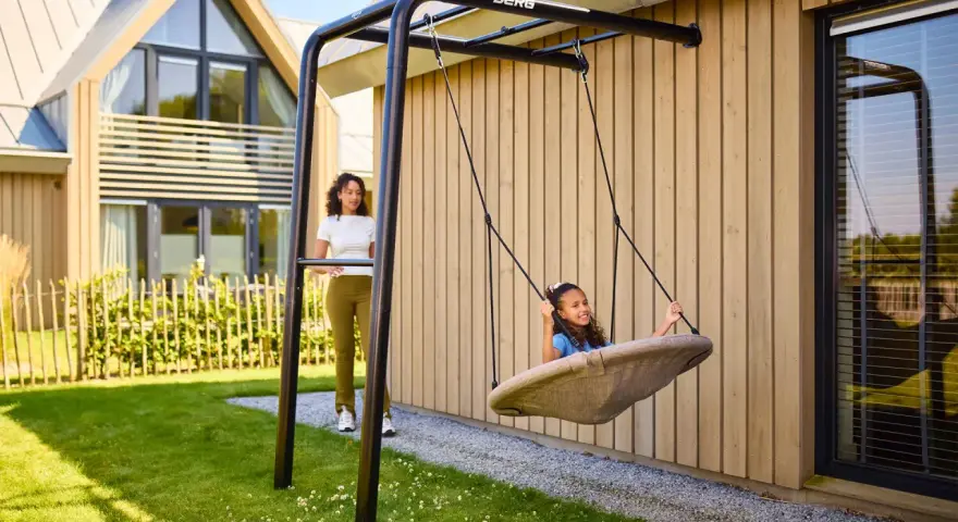 Tolle spielecke garten ideen kinder: Ein Mädchen schaukelt fröhlich, während eine Frau zusieht.