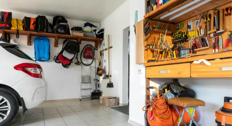 Praktische garage einrichten ideen: Werkzeugwand, Regale mit Taschen und ein Kompressor schaffen Ordnung.